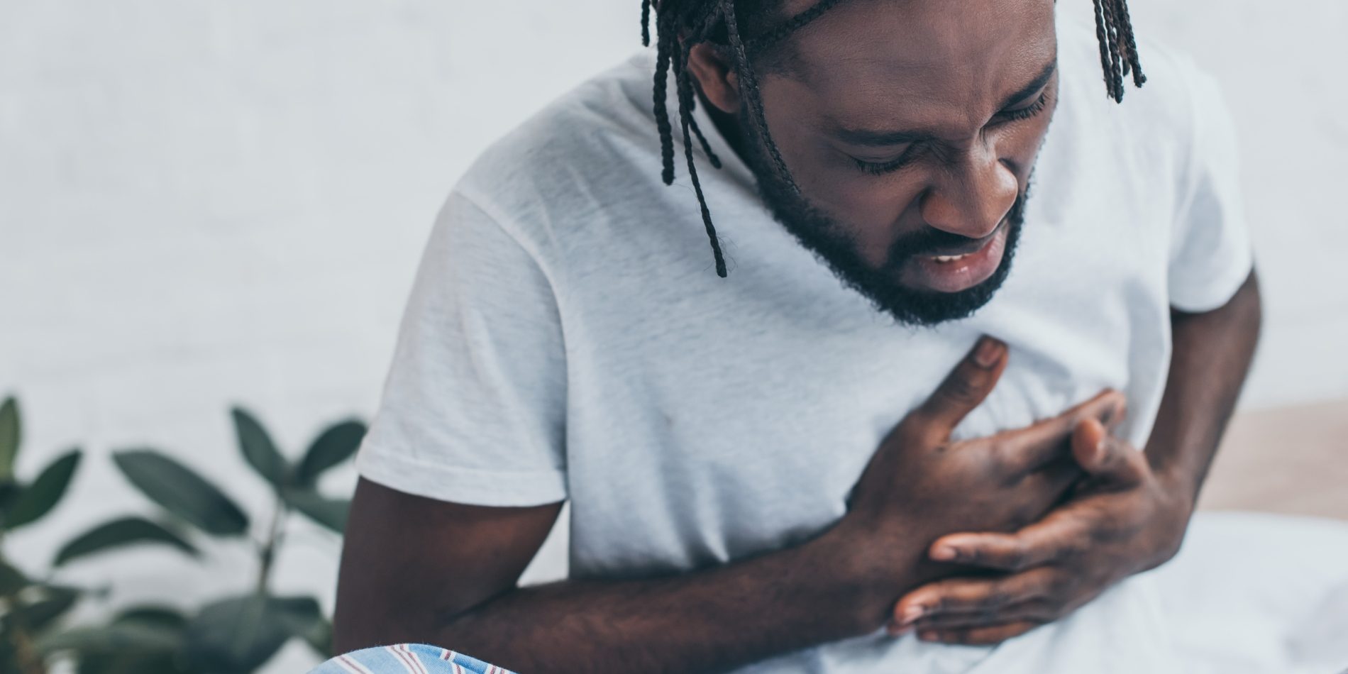 young african american man suffering from heart pain in bedroom